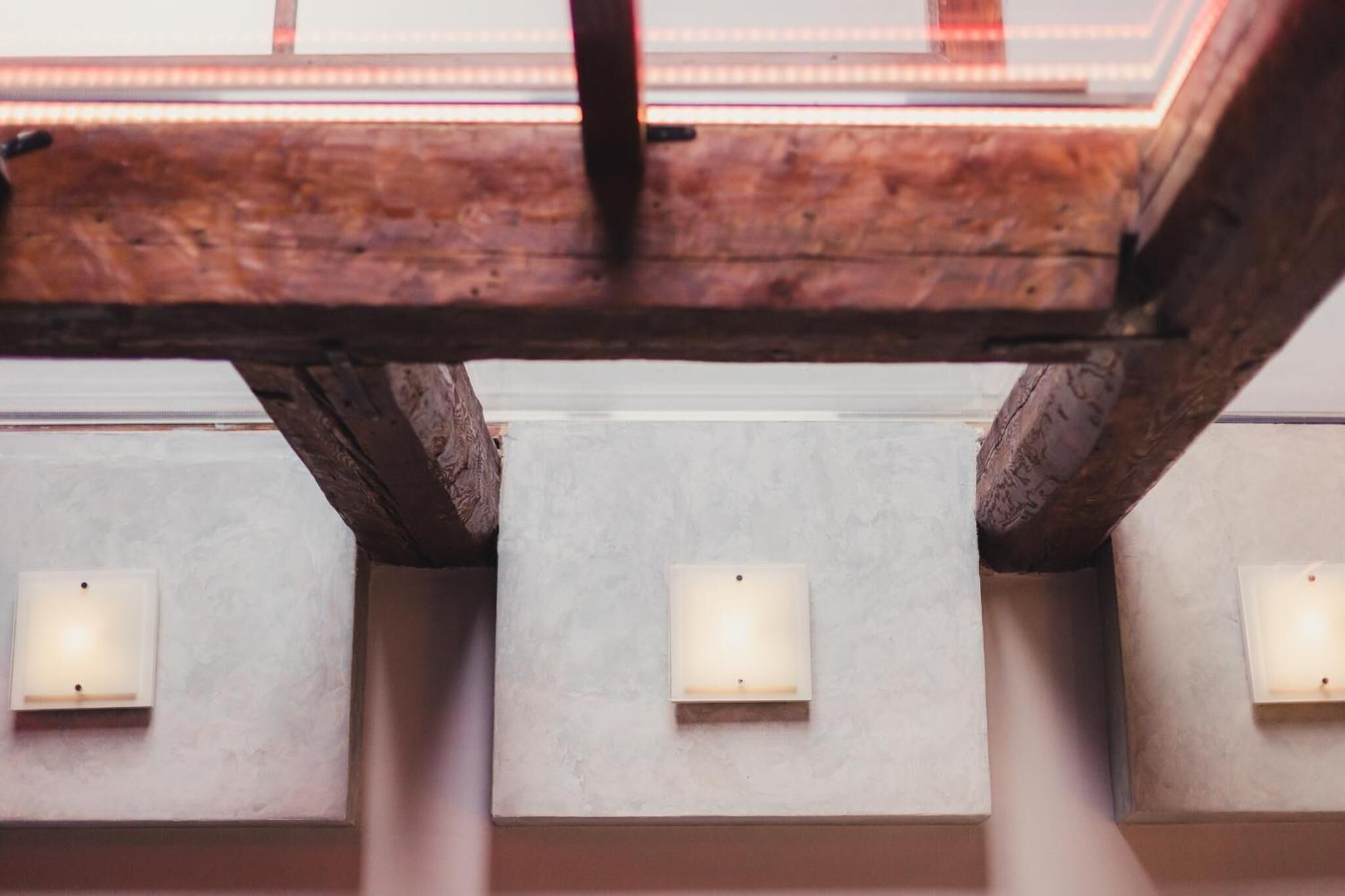 A ceiling with wooden beams and recessed lighting fixtures.