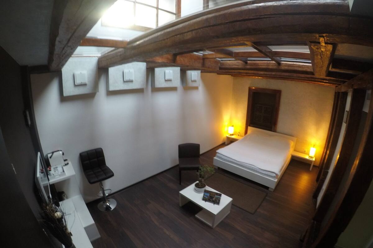 Ein modernes Hotelzimmer mit einem großen Bett, zwei Sesseln, einem kleinen Tisch und einem Schreibtisch mit einer Lampe.