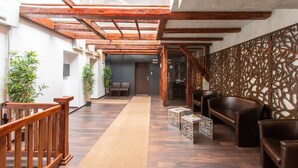 A hallway with wooden beams, a carpeted path, and seating areas with chairs and tables. - Vendi Grand Square Residence (Sibiu)