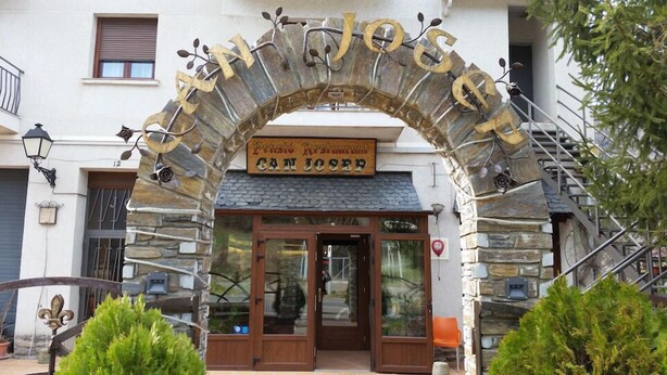 Entrada de un restaurante con un arco de piedra, puertas de madera y un cartel sobre la entrada.