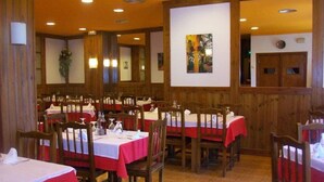Un restaurante con paredes de madera, manteles rojos y blancos, y un cuadro grande en la pared.