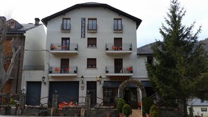 Un edificio de varios pisos con balcones, un garaje y una entrada con arco de piedra.