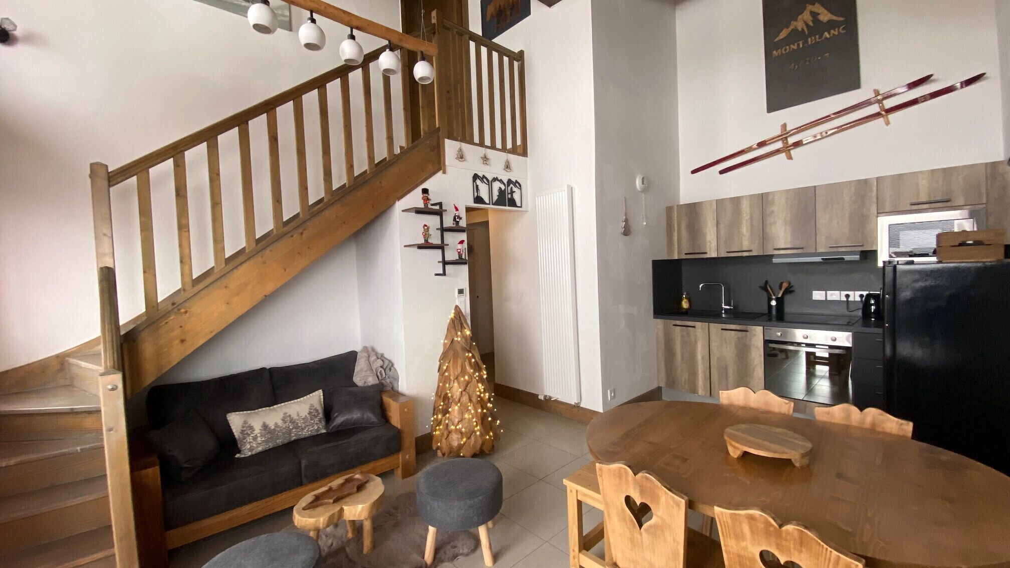 A modern kitchen with wooden cabinets, a black refrigerator, and a dining table with wooden chairs.