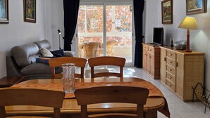 A dining area with a wooden table, chairs, a sofa, and a TV on a wooden cabinet. - Celio I by Interhome (Albir)