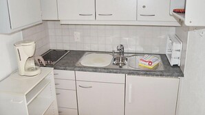 A compact kitchen with white cabinets, a sink, a coffee maker, and a toaster. - Residenza Corallo by Interhome (Ascona)