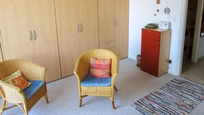 A room with a wicker chair, a red cabinet, and a large wardrobe. - Residenza Corallo by Interhome (Ascona)