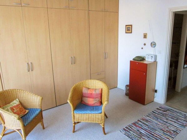 A room with a wicker chair, a red cabinet, and a large wardrobe. - Residenza Corallo by Interhome (Ascona)