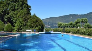 A swimming pool with clear blue water, surrounded by lush greenery and a mountain in the background.