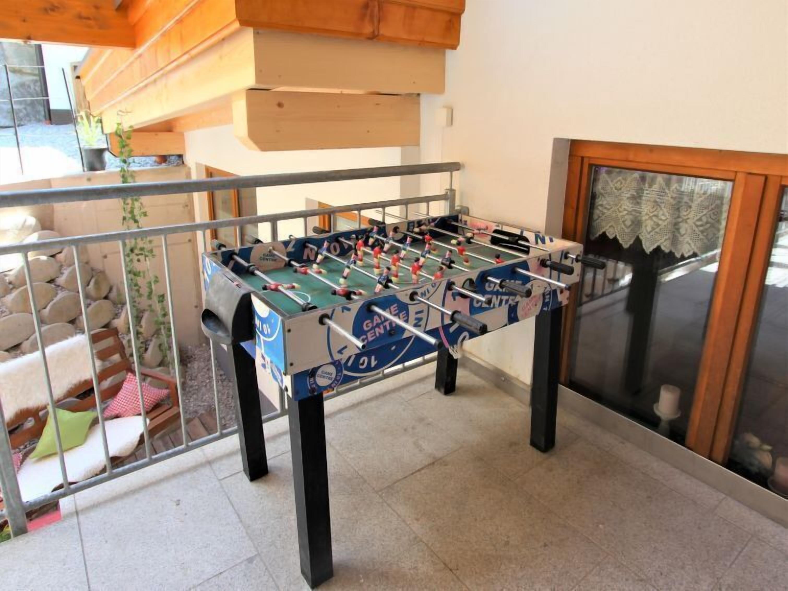 A foosball table in a room with a stone wall and a window.