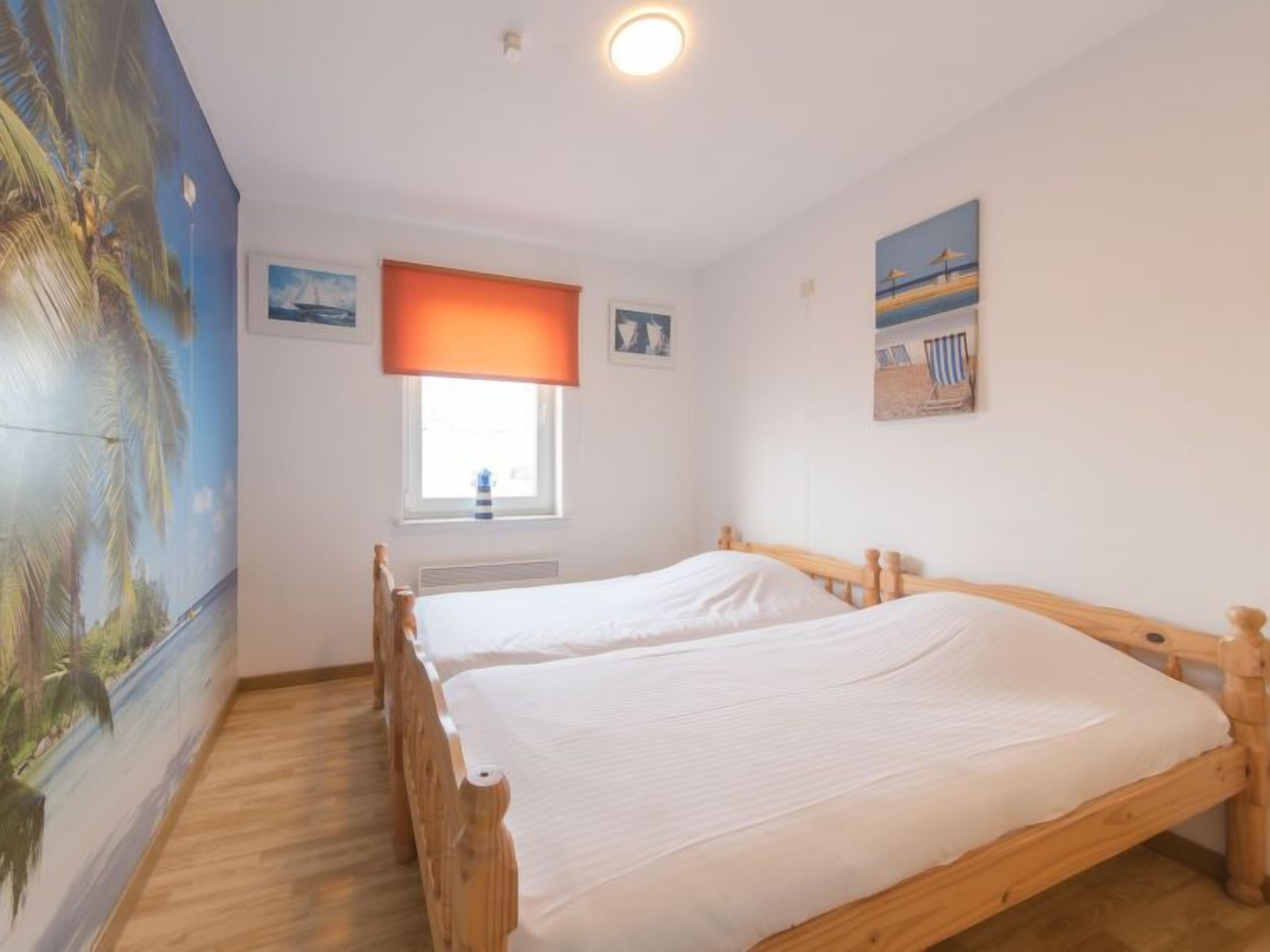 A bedroom with two wooden beds, a window with a view, and a beach-themed wall mural.