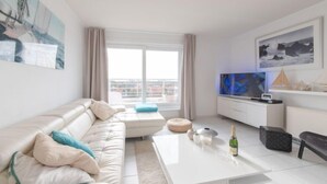 A modern living room with a white sofa, a coffee table, and a TV.