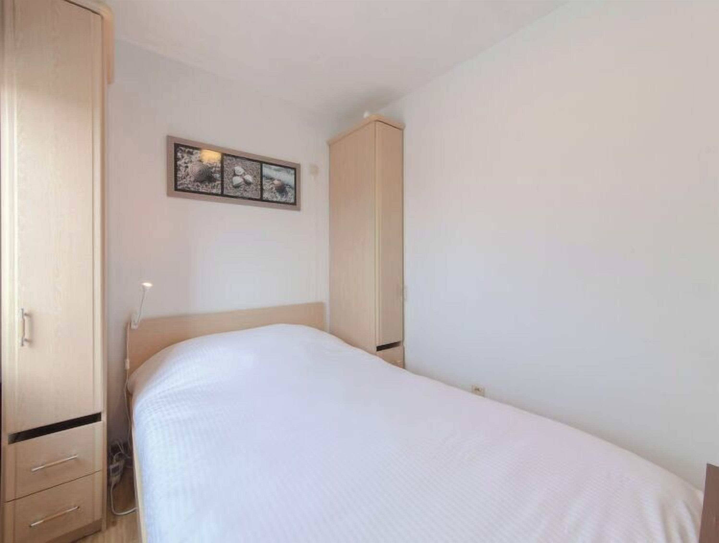A bedroom with a bed, a wardrobe, and a framed picture on the wall.