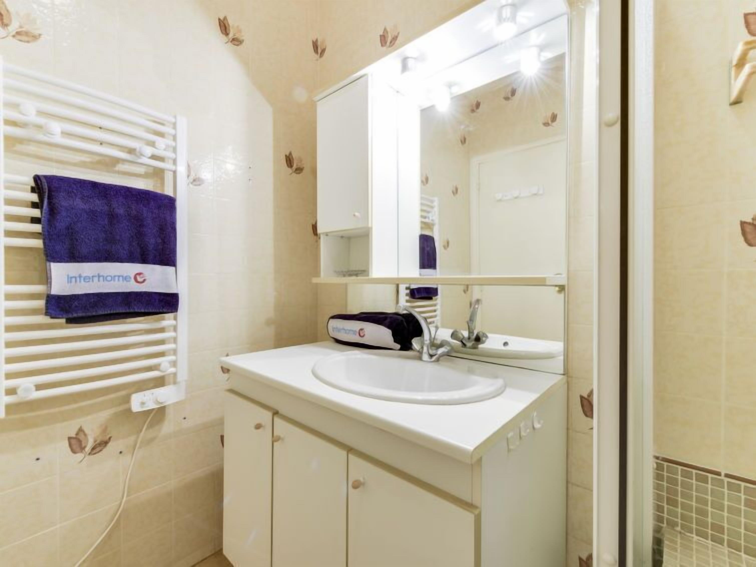 A bathroom with a white sink, a mirror, and a towel rack with a blue towel.