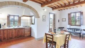 Una cocina rústica con armarios de madera, una mesa de comedor para dos personas y un banco en la zona de comedor.