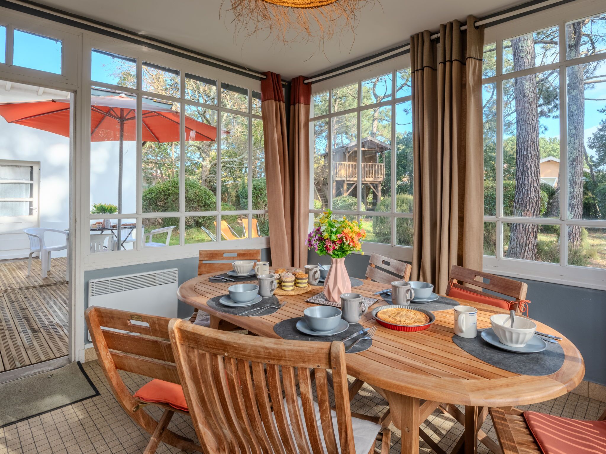 A dining area with a round wooden table, chairs, and a view of the outdoors.