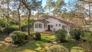 Una casa blanca con tejado de baldosas, rodeada de árboles y arbustos.