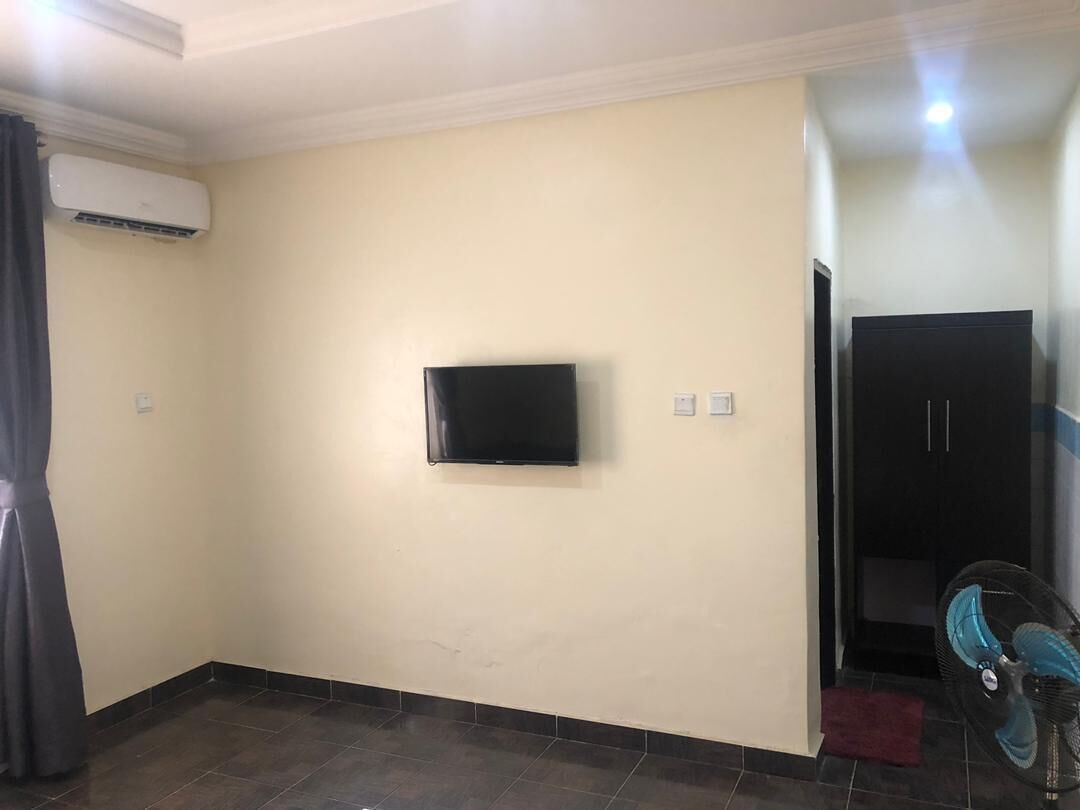 Une pièce dotée d’un téléviseur à écran plat fixé au mur, d’un ventilateur de plafond et d’une porte donnant sur une autre pièce.
