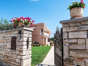 A two-story building with a stone facade, a balcony, and a pathway leading to the entrance. - Mirjana by Interhome (Barban)