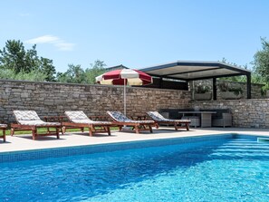 A swimming pool with lounge chairs and a covered seating area. - Mirjana by Interhome (Barban)