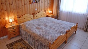 A wooden-paneled bedroom with a bed, two bedside tables, and a nightstand. - Metropol A 13 by Interhome (Grächen)