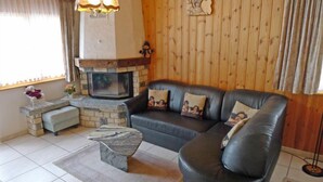 A cozy living room with a stone fireplace, a leather sofa, and a small table. - Metropol A 13 by Interhome (Grächen)