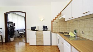 A compact kitchen with white cabinets, a wooden countertop, a microwave, and a coffee maker.