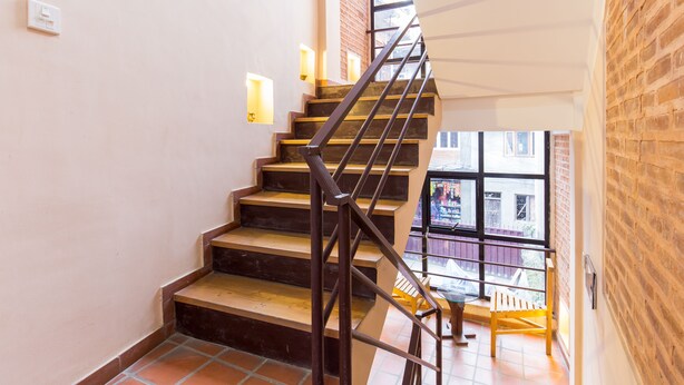 A staircase with wooden steps and metal railings, leading to a balcony with a view of the outside. - Team Yala Inn (Lalitpur)