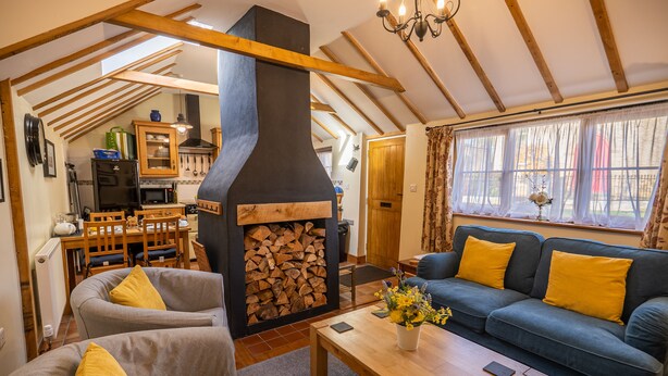Ein gemütliches Wohnzimmer mit Kamin, Holzbalken, einer Couch und einem Essbereich.