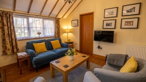Ein gemütliches Wohnzimmer mit einem blauen Sofa, einem grauen Sofa, einem Holztisch und einem an der Wand befestigten Fernseher.