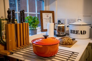 A kitchen with a red pot, a loaf of bread, a toaster, and a wooden knife block. - All Seasons Cottage Breaks (Saxmundham)