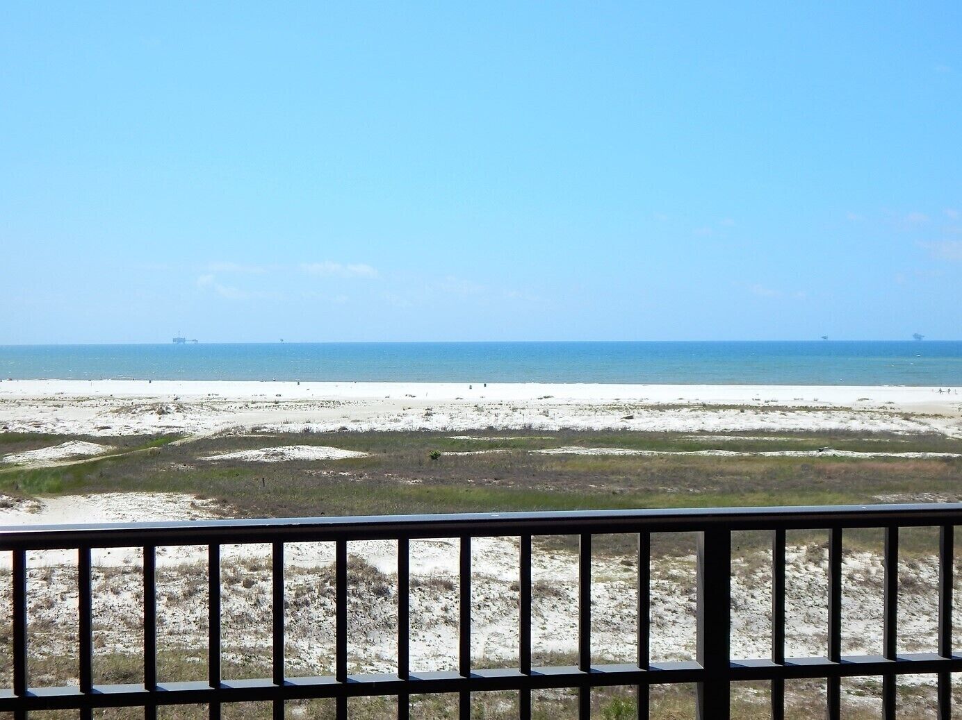 A beach with a clear view of the ocean and distant ships.