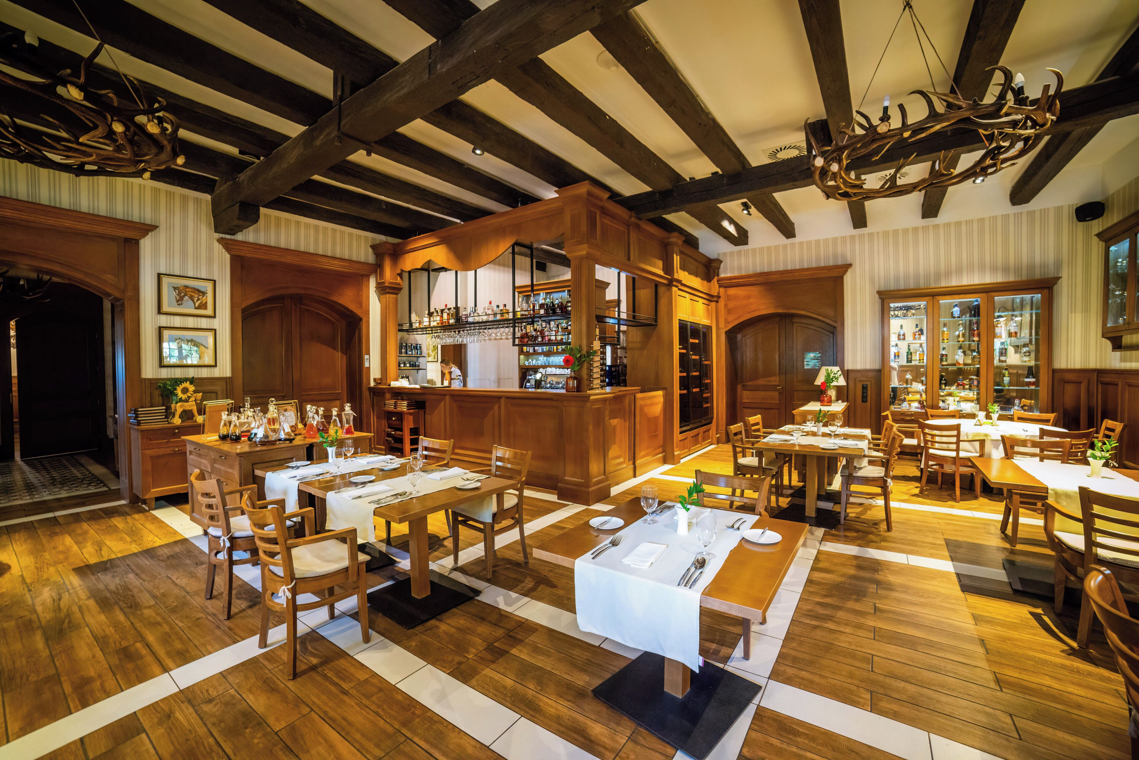 Un restaurante con suelo de madera, mesas dispuestas para comer y una zona de bar.