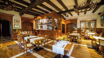 Un restaurante con suelo de madera, mesas dispuestas para comer y una zona de bar.