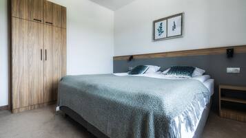 A bedroom with a bed, wooden wardrobe, and a framed picture on the wall.