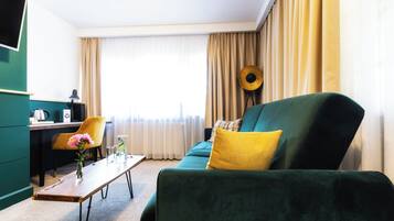 Uma sala de estar moderna com um sofá verde, um travesseiro amarelo, uma mesa de centro de madeira e uma cadeira amarela.