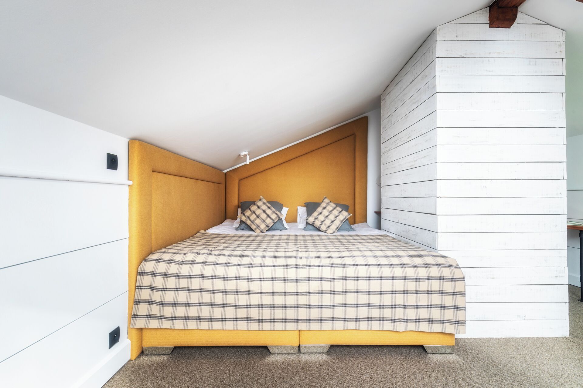 A bedroom with a bed, headboard, and white walls.