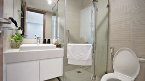 A modern bathroom with a glass-enclosed shower, a white sink, and a toilet.