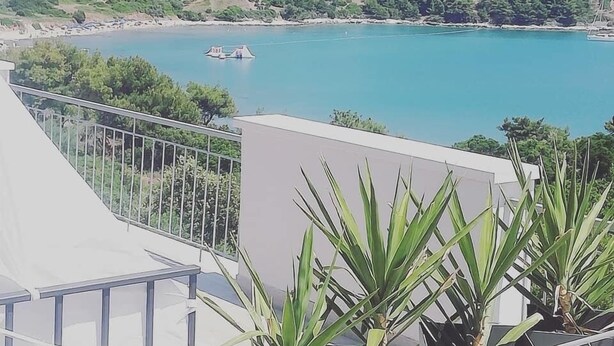 A balcony with a view of a coastal area, including a beach and a boat. - Apartments Pržina (Lumbarda)