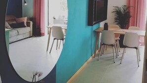 A modern living room with a sofa, a dining area with a table and chairs, and a TV mounted on the wall. - Apartments Pržina (Lumbarda)