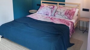 A bedroom with a bed, two bedside tables, a wall-mounted lamp, and a wall decoration. - Apartments Pržina (Lumbarda)