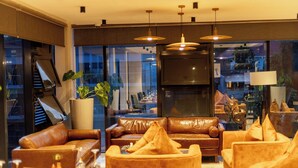 A modern living room with leather sofas, a large TV, and pendant lighting. - Mythos Boutique Hotel (Kigali)