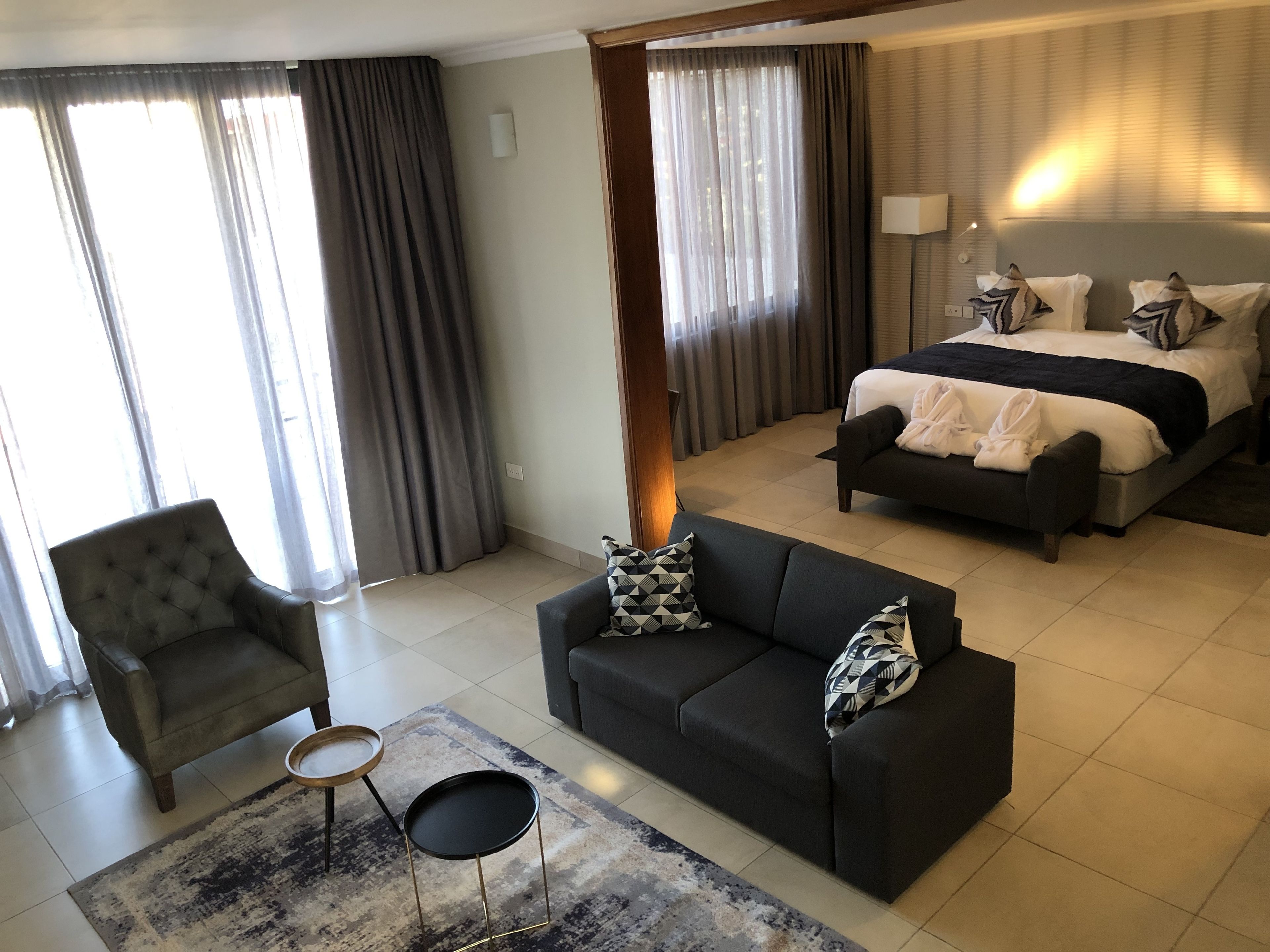 A hotel room with a bed, a sofa, a chair, and a small table.