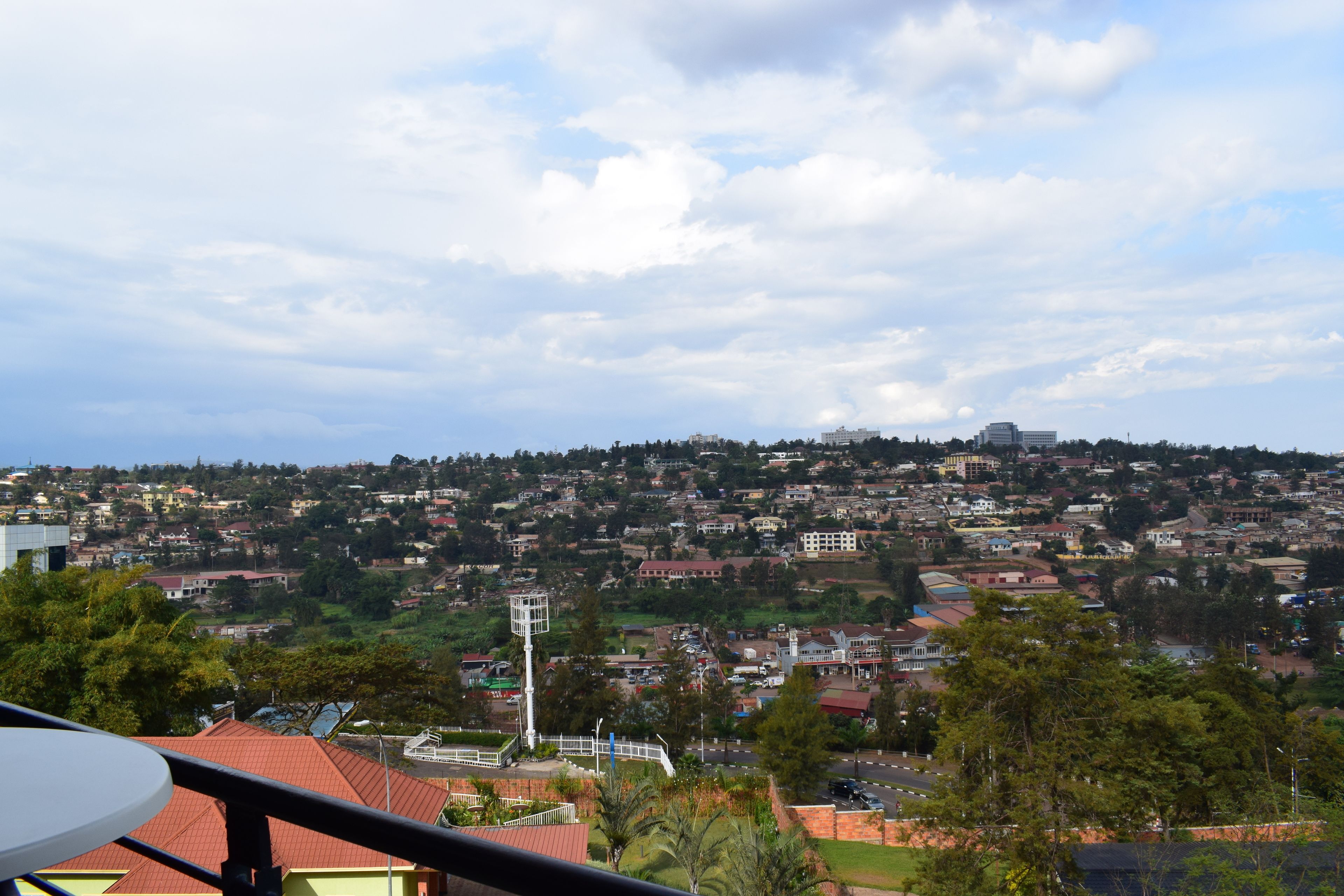 A panoramic view of a cityscape with residential buildings, a prominent white tower, and a clear sky.