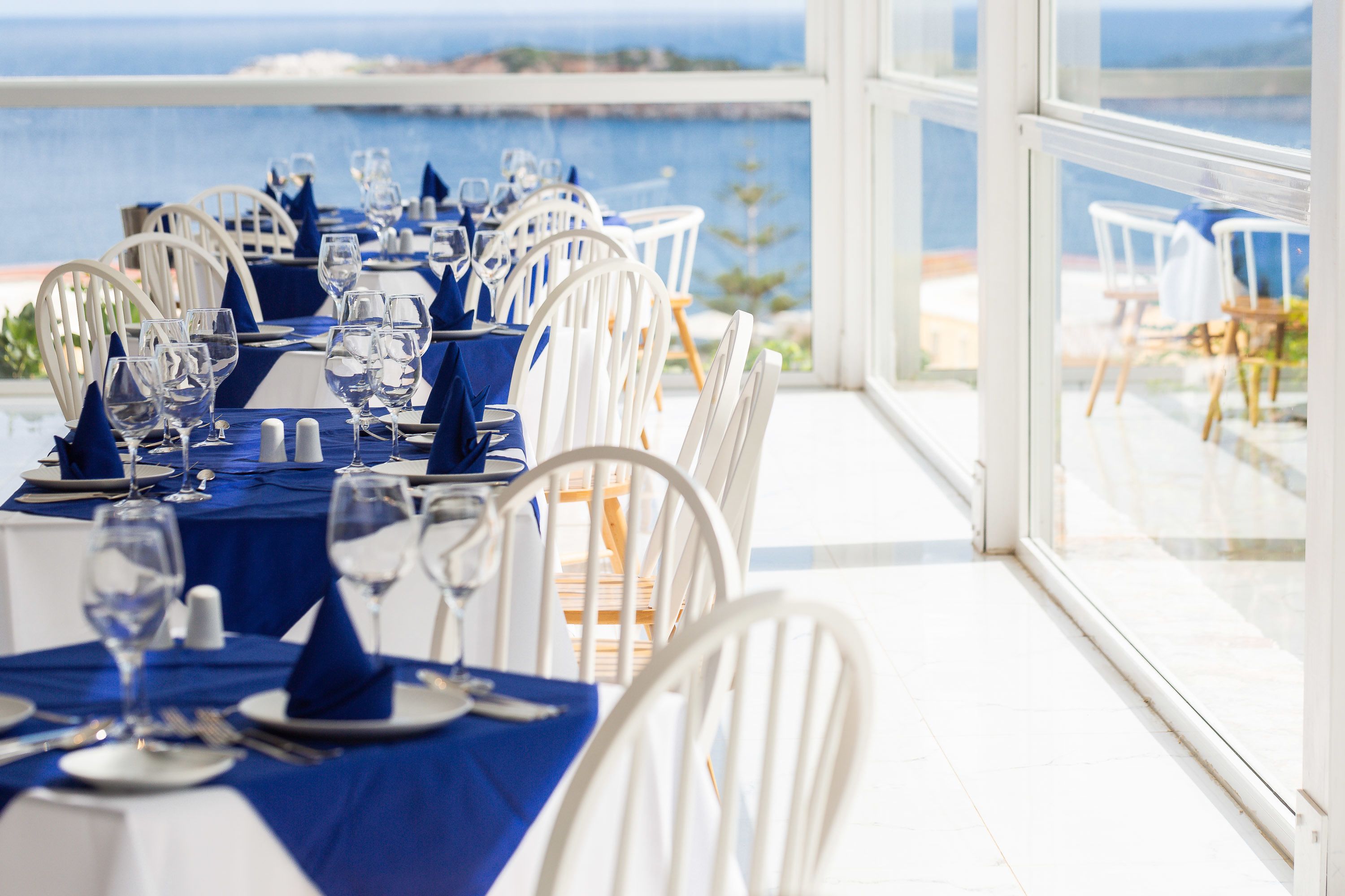 A dining area with tables set for a meal, overlooking a body of water.