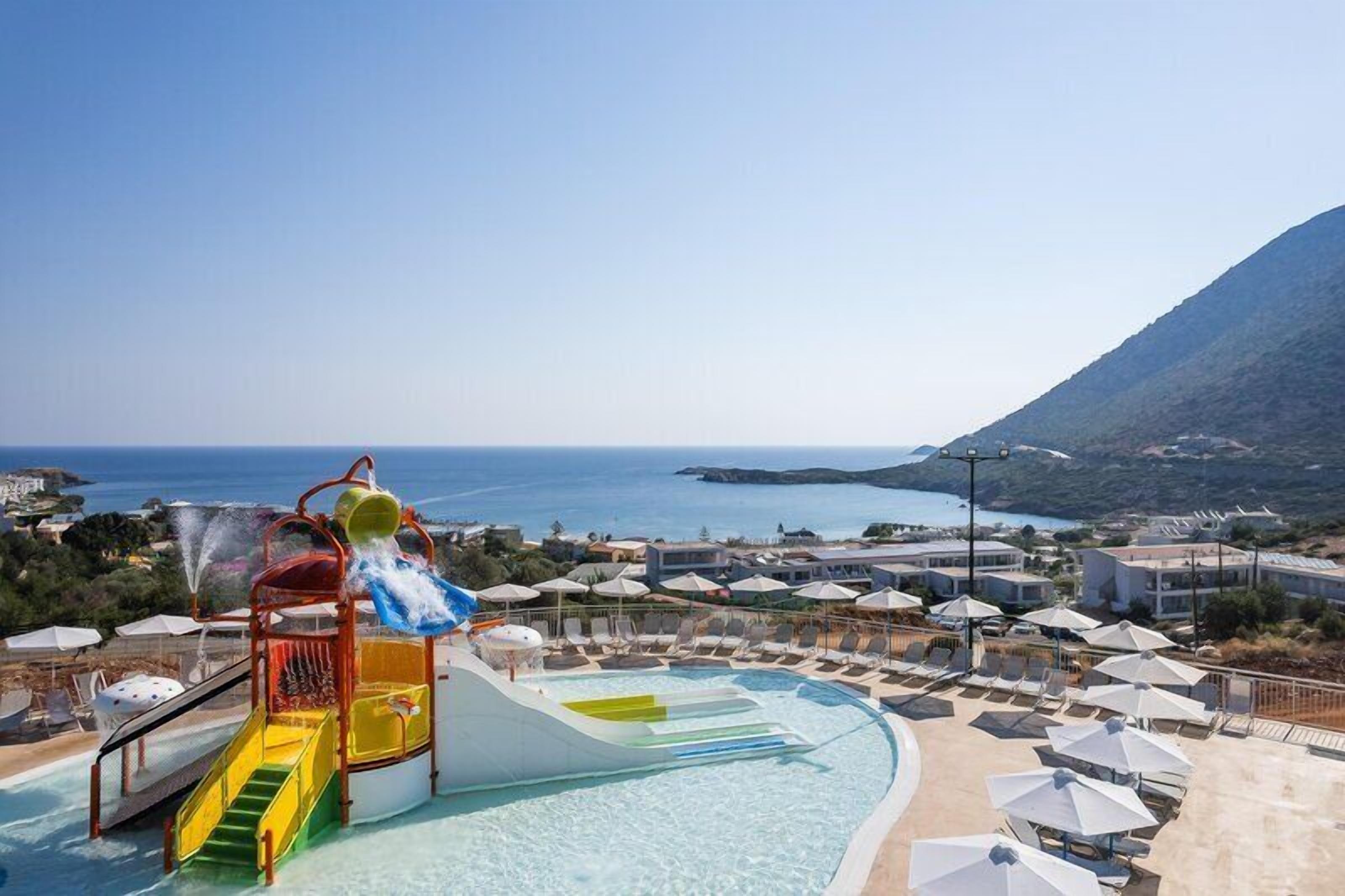 Una piscina al aire libre, sombrillas, sillones reclinables de piscina