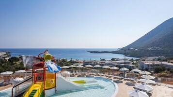 Una piscina al aire libre, sombrillas, sillones reclinables de piscina