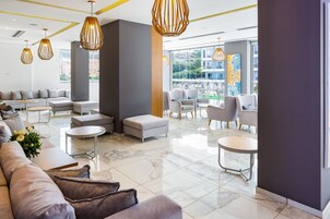 Un moderno vestíbulo de hotel con un sofá modular, otomanas y una zona de estar con sillas.
