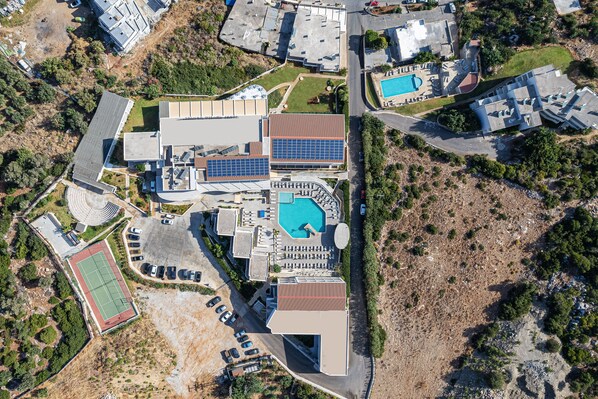 Vue aérienne d’un quartier résidentiel comprenant plusieurs immeubles, une piscine et un court de tennis.