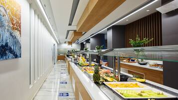 Un pasillo de hotel con una zona de bufé que ofrece diversos alimentos y un gran cuadro abstracto en la pared.