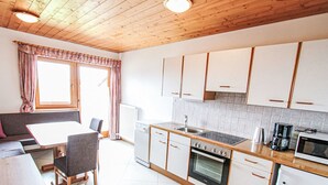 Una cocina moderna con armarios blancos, encimera de madera y comedor con mesa y sillas.